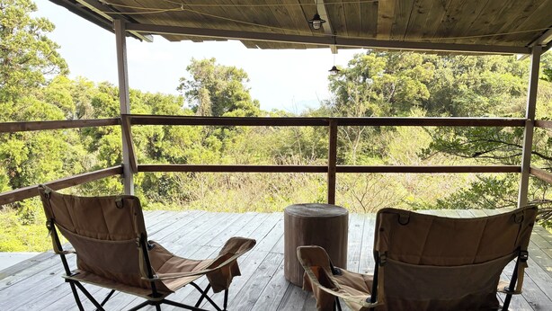 A covered outdoor area with two folding chairs and a wooden table. - A mountain house for forest bathing in a hidden and unexplored part of Yakushima (屋久島町)
