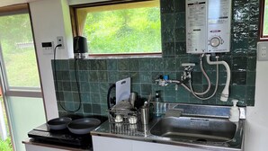 A kitchen with a sink, stove, and a window with a view of greenery. - A mountain house for forest bathing in a hidden and unexplored part of Yakushima (屋久島町)