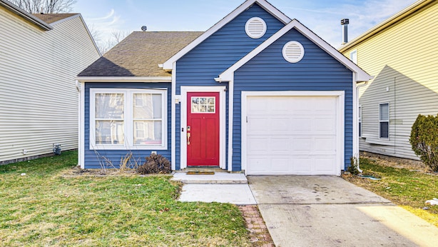 A two-story house with a red front door, a garage, and a small front yard. - 5 Mi to Eagle Creek Park: Home w/ Fenced Yard! (Indianapolis)