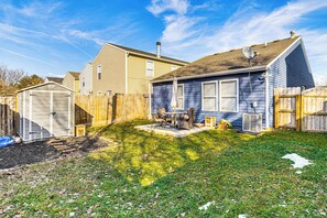 Un jardin à l’arrière d’une maison, avec une maison, une clôture en bois et un abri de jardin.