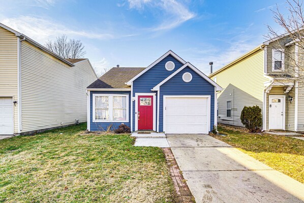 A single-story house with a red front door, a garage, and a small front yard. - 5 Mi to Eagle Creek Park: Home w/ Fenced Yard! (Indianapolis)