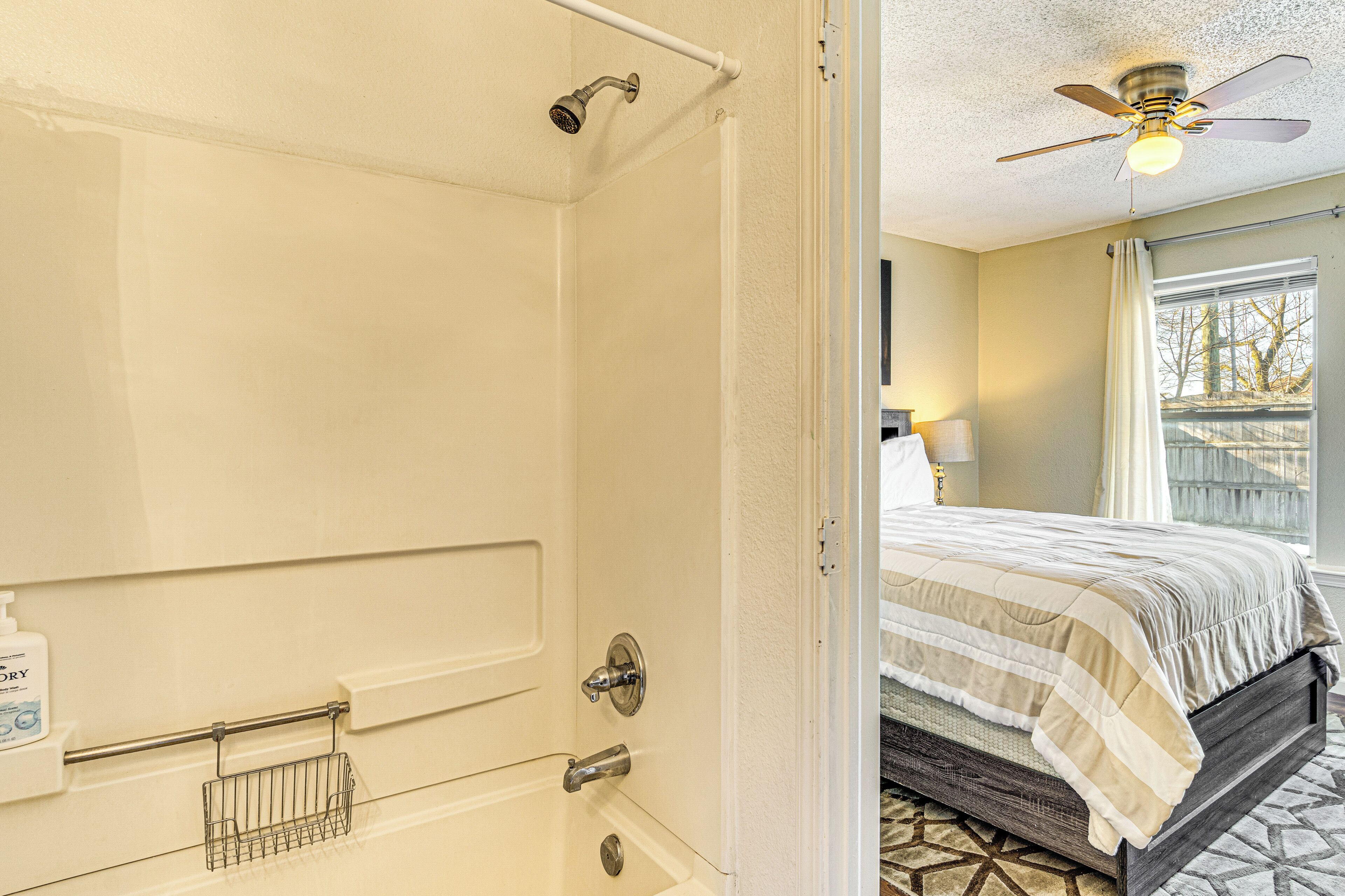 A bathroom with a shower, a towel rack, and a bottle of hand soap.