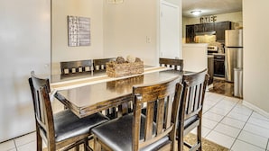 A dining area with a wooden table and chairs, a hanging light fixture, and a kitchen in the background. - 5 Mi to Eagle Creek Park: Home w/ Fenced Yard! (Indianapolis)