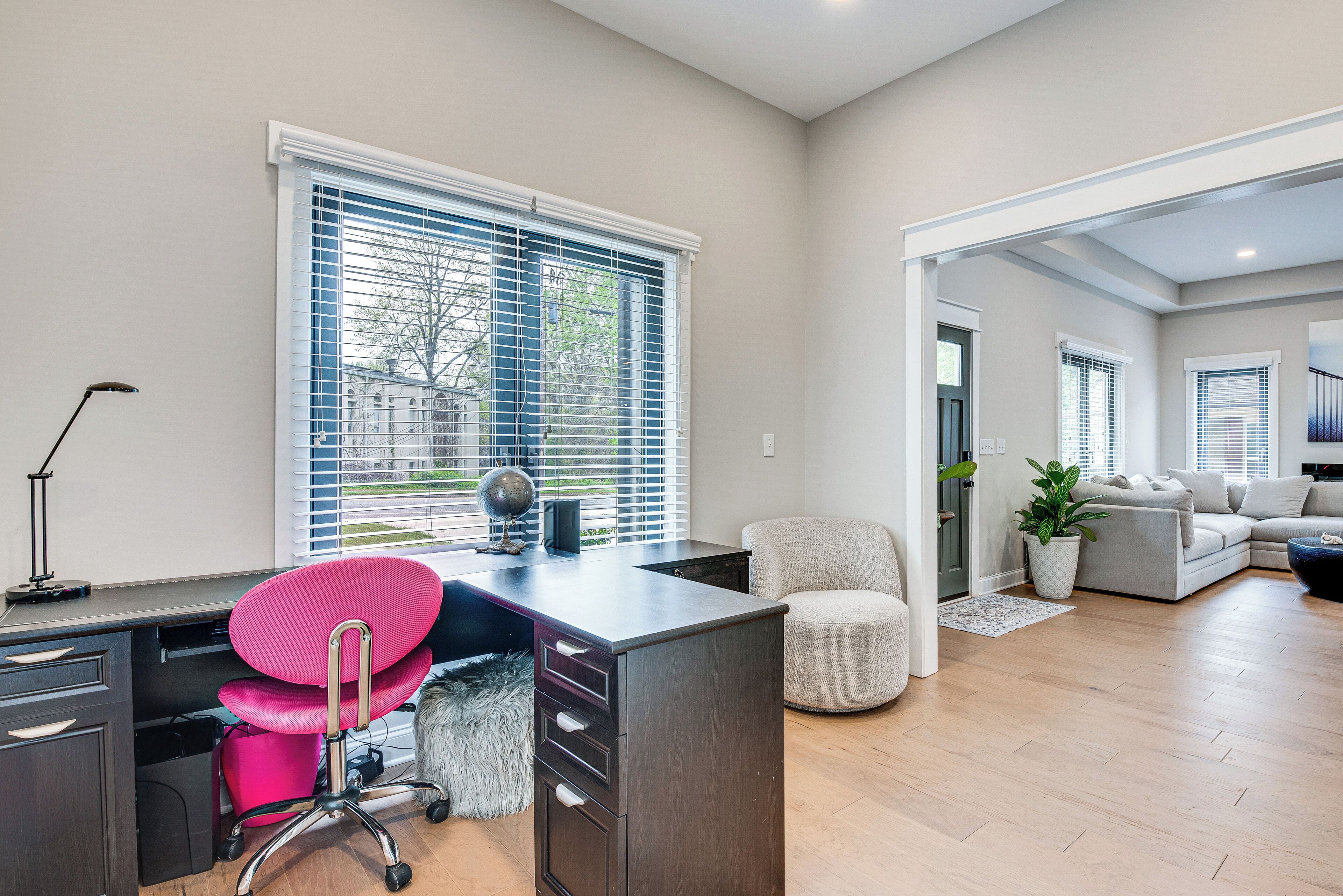 A modern office space with a desk, chair, and a view of the outside through large windows.