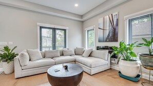 A modern living room with a sectional sofa, a round coffee table, and potted plants. - 3 Mi to Mercedes-benz: Home w/ Office & Backyard! (Atlanta)