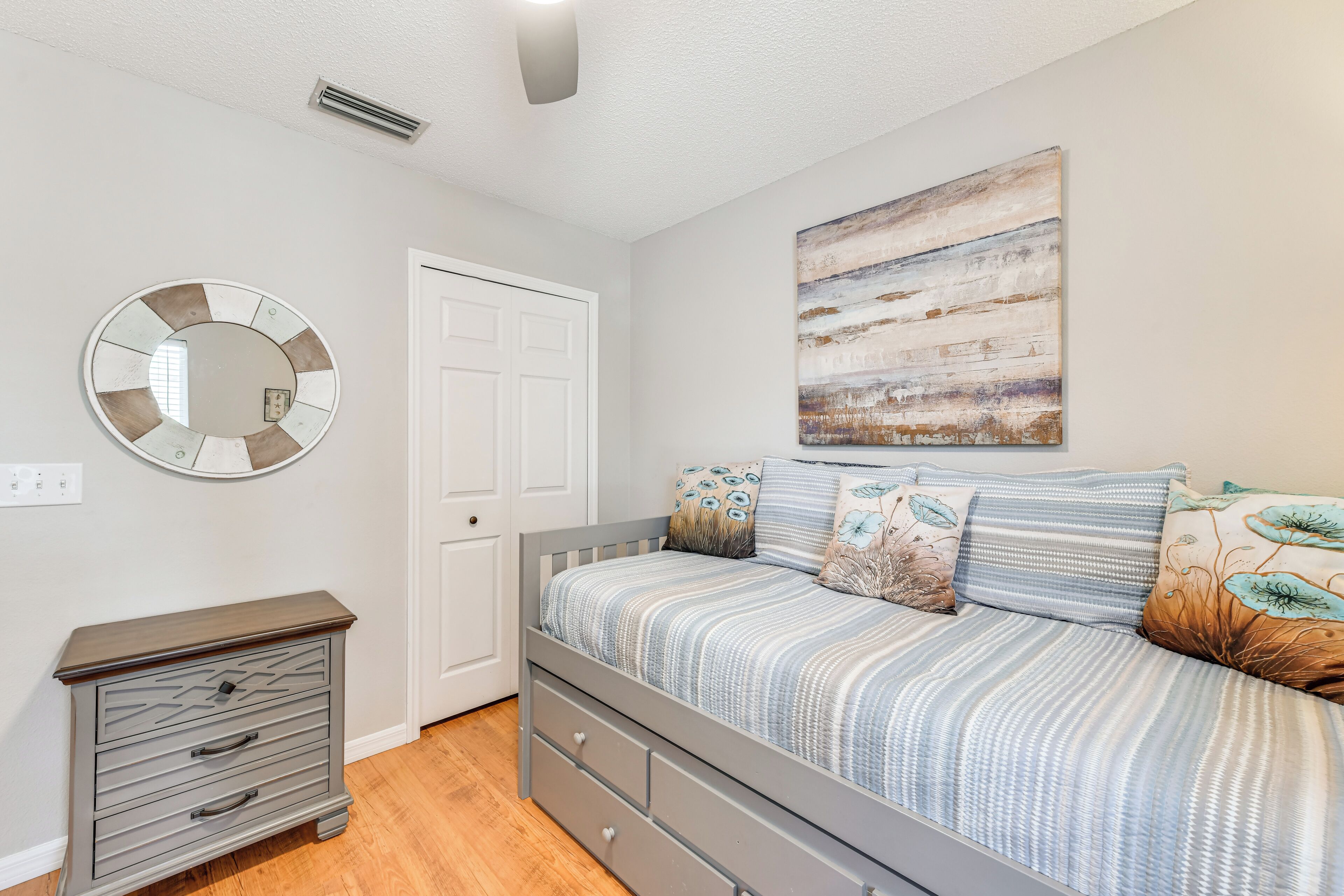 Une chambre à coucher avec un lit, une commode, un miroir et une porte.