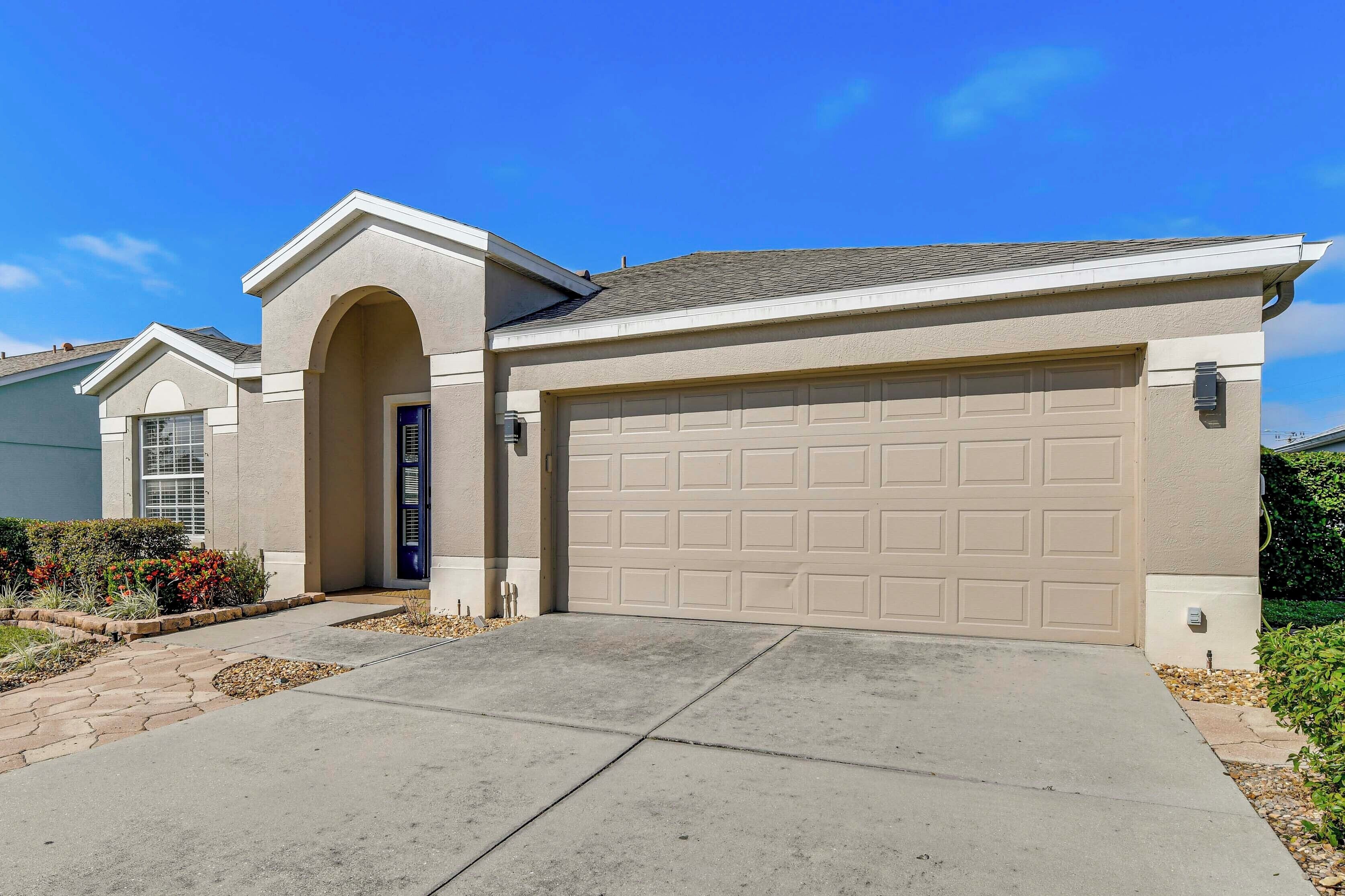 A single-story house with a beige garage door, a small attached garage, and a front entrance with a door.
