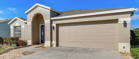 A single-story house with a beige garage door, a small attached garage, and a front entrance with a door.