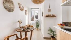 Cozinha moderna com área de refeições, apresentando uma mesa redonda, cadeiras de madeira e uma luminária pendente.