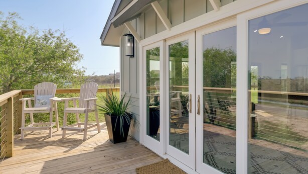 A deck with two white chairs, a potted plant, and a glass door leading to a patio area. - 3 Mi to Rockport Beach: Home Near Aransas Bay (Rockport)