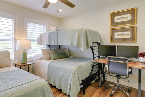 A bedroom with a bunk bed, a desk with a computer, and two framed fish pictures on the wall.
