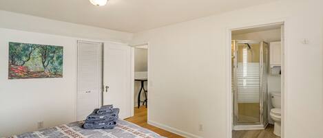 A bedroom with a bed, a painting, and a closet.