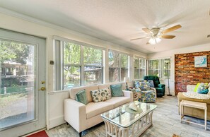 A sunroom with a white sofa, glass coffee table, and a brick accent wall. - Boat Slip & Fire Pit: Peaceful House (Homosassa)