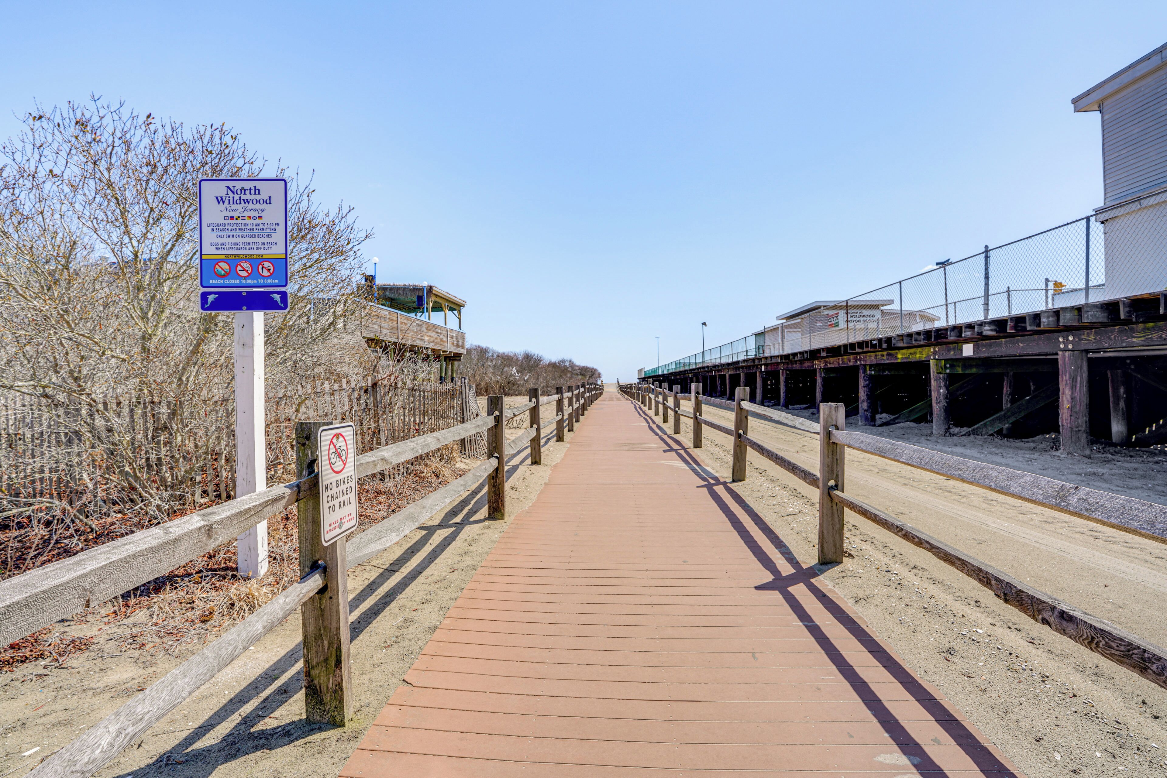A wooden boardwalk leading to a beach area with a sign indicating no bikes allowed.