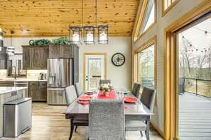 A modern kitchen with wooden cabinets, a stainless steel refrigerator, and a dining area with a table set for four.