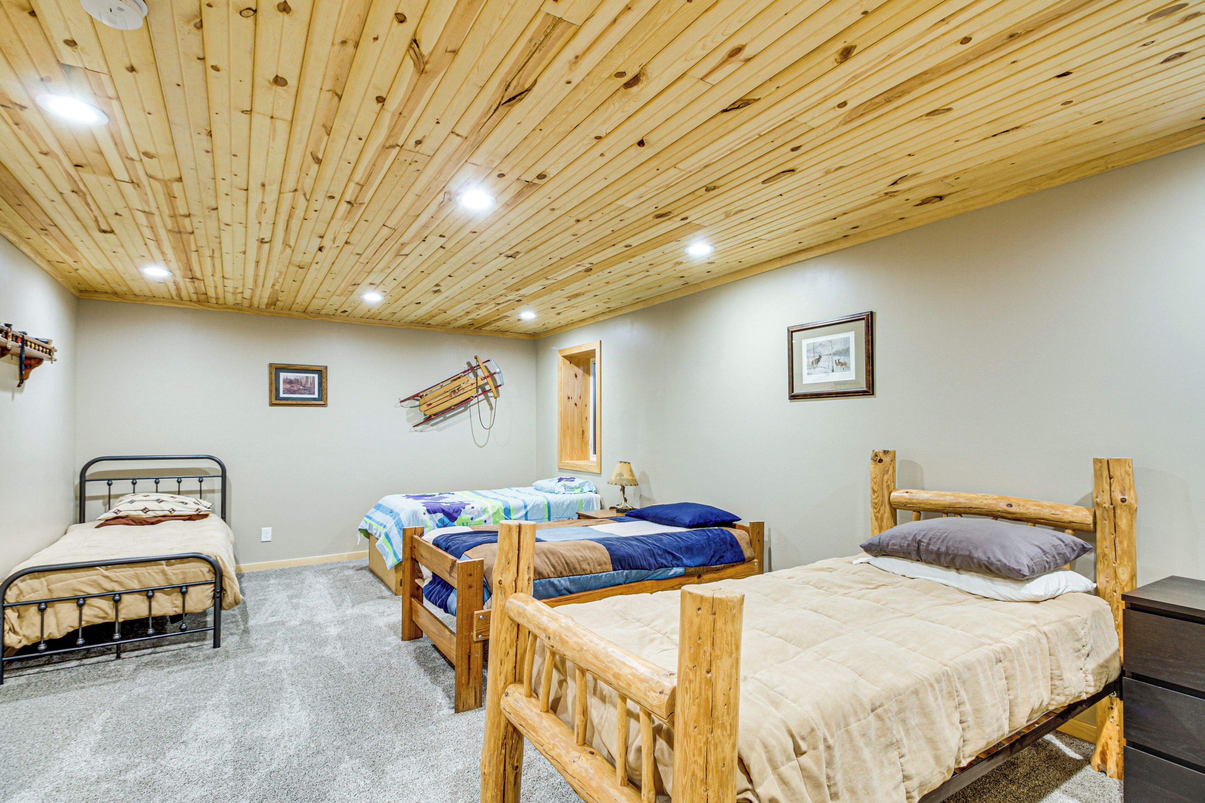A room with three wooden beds, a ceiling with wooden beams, and a carpeted floor.