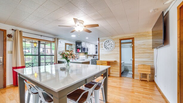 A spacious kitchen with a central island, wooden flooring, and a ceiling fan.