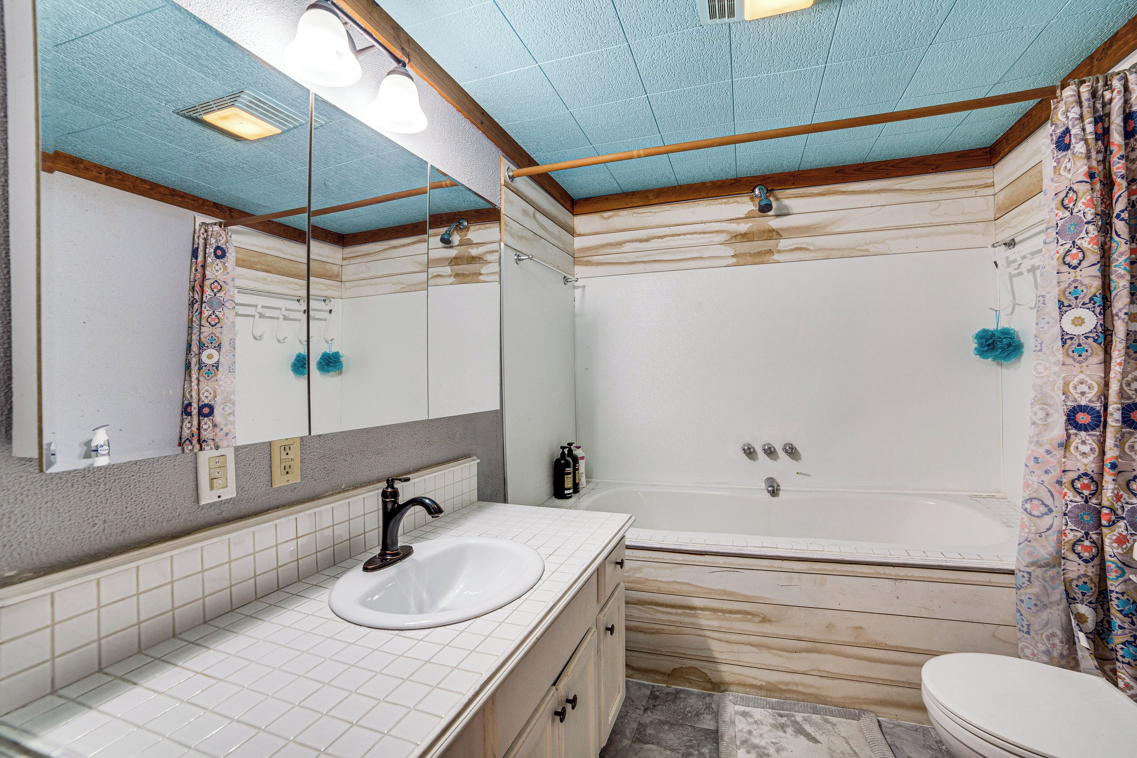 A bathroom with a white sink, mirror, and bathtub.