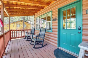 Une cabane en bois avec une porte turquoise, des fauteuils à bascule et un porche abrité.