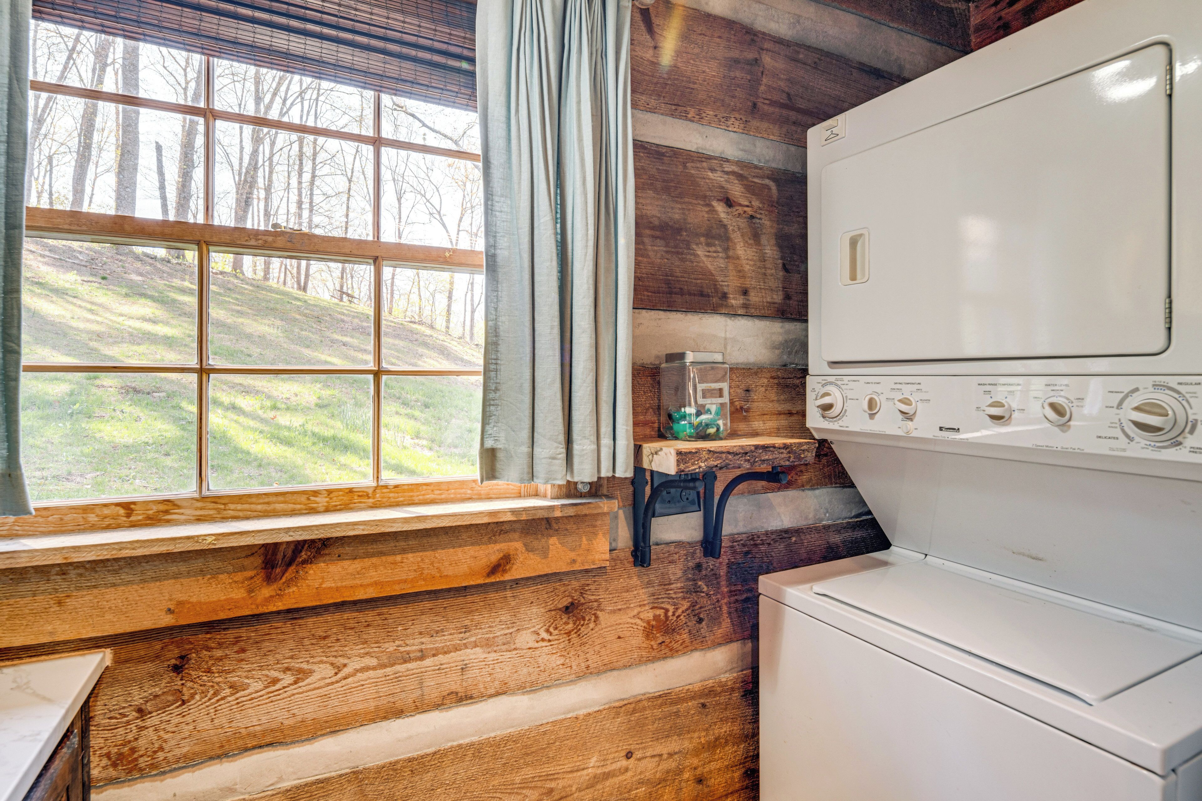 A laundry room with a large window, wooden walls, and a white washing machine.