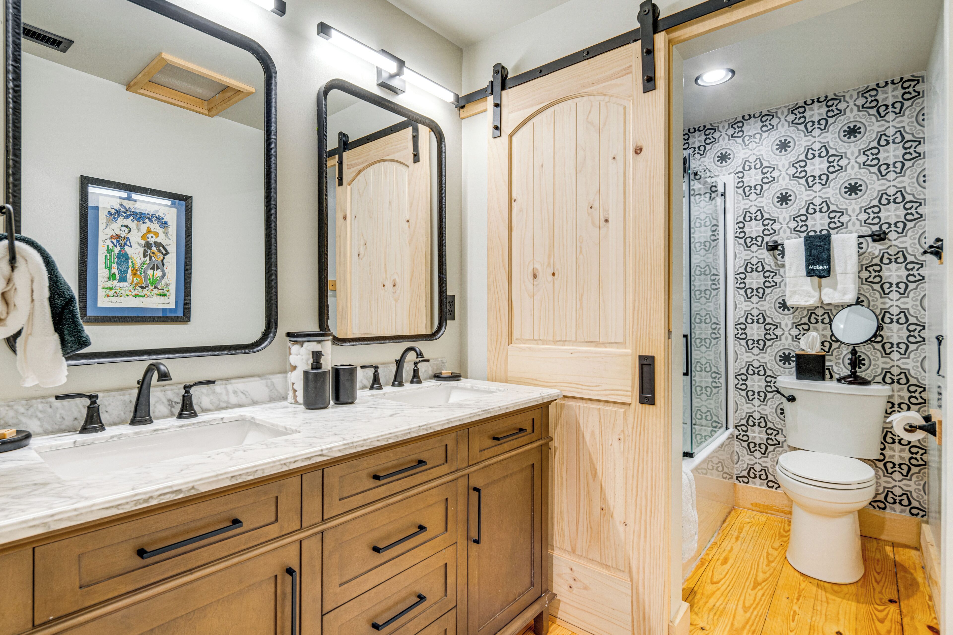 A bathroom with a wooden vanity, a large mirror, a sink, and a toilet.