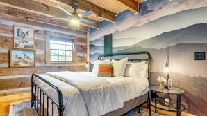 Ein Schlafzimmer mit einem Bett, einem runden Glastisch, einem Deckenventilator und einer Bergwand.