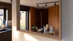 A modern kitchen with a large mirror reflecting a dining area. - Modern 2-bed Cabin Near West Wittering Beach (Chichester)