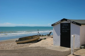 Un pequeño edificio blanco con una puerta negra con la leyenda 'FISHERMAN'S HUT' y un letrero que indica que está abierto de 11:30 a 1.