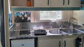 A compact kitchen with a sink, a small refrigerator, and a window providing natural light.