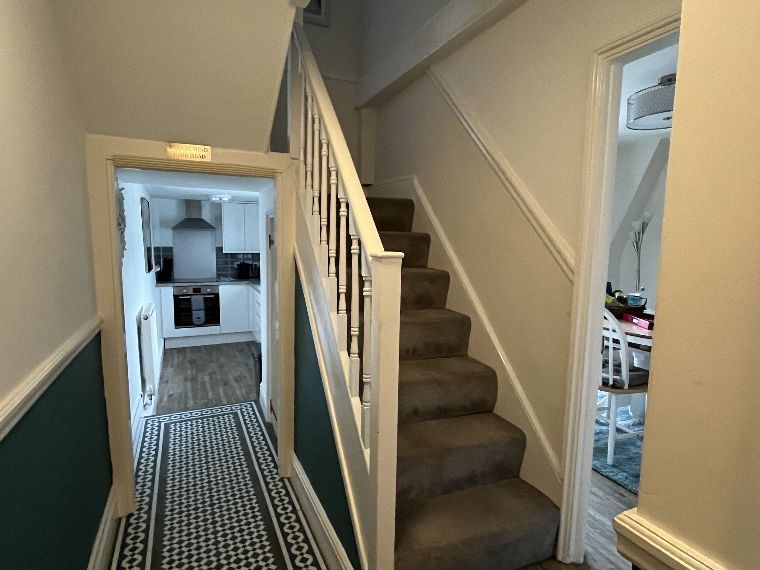A narrow hallway with a patterned floor leading to a staircase.