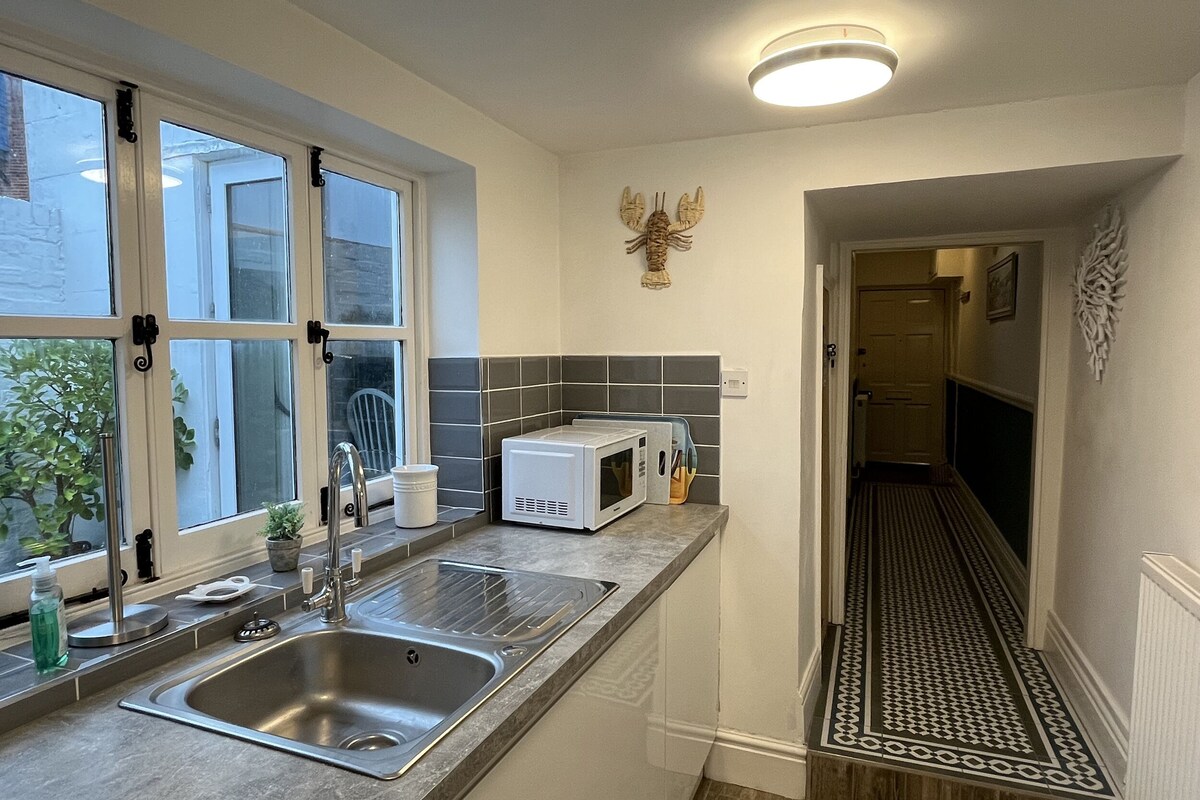 A modern kitchen with a stainless steel sink, a microwave, and a window with a view of greenery outside.