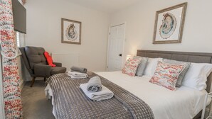 Un dormitorio con una cama, una silla y una puerta.