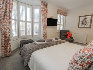 A bedroom with a bed, a chair, a TV, and a radiator.