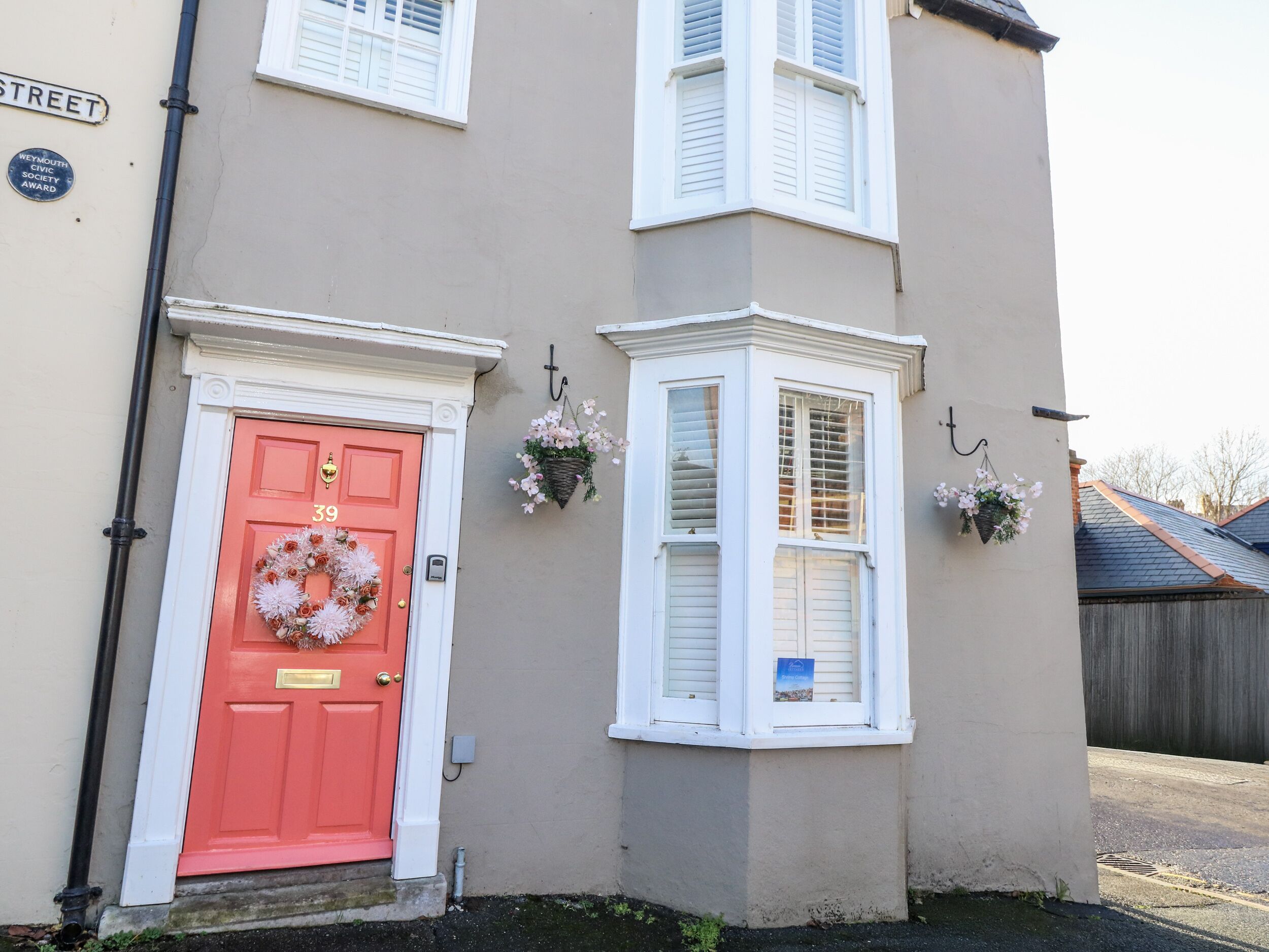 A building with a red door, white shutters, and a street sign.
