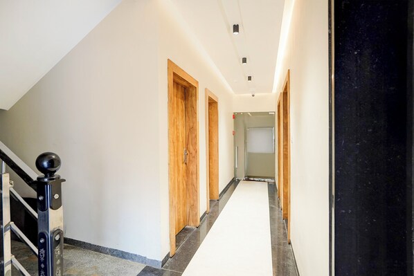 A long, narrow hallway with wooden doors and a black balustrade on the left.