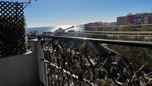 En balkon med havudsigt, gelænder og bygninger i baggrunden.