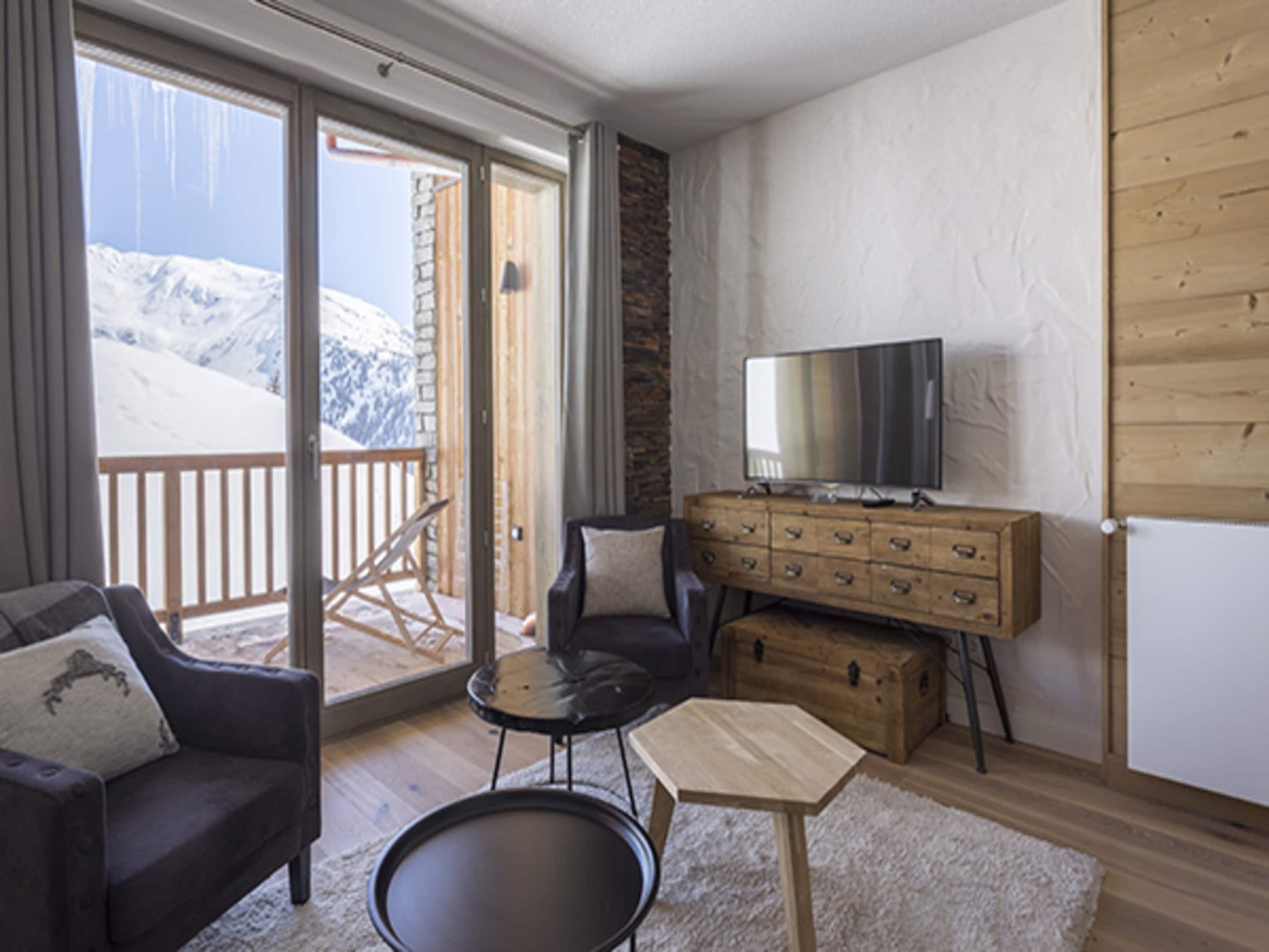A cozy room with a sofa, a small table, a TV, and a wooden chest of drawers.