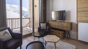 A cozy room with a sofa, a small table, a TV, and a wooden chest of drawers. - Apartment in La Rosiere With Alpine Views (Montvalezan)