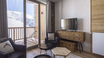 A cozy room with a sofa, a small table, a TV, and a wooden chest of drawers.