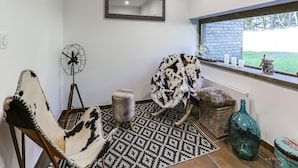 A cozy room with a patterned rug, a rocking chair, a fan, and a window with a view of greenery. - Apartment in La Rosiere With Alpine Views (Montvalezan)