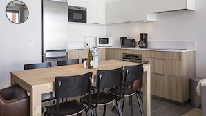 A modern kitchen with white cabinets, a wooden dining table, and black chairs. - Apartment in La Rosiere With Alpine Views (Montvalezan)