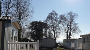 Une rangée de maisons mobiles avec une cour clôturée, des arbres et un ciel dégagé.
