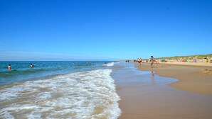 Una playa con gente nadando y caminando por la orilla.