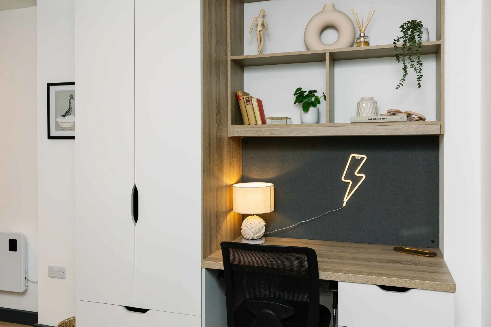 Un espacio de oficina moderno con escritorio, silla y estante con objetos decorativos.
