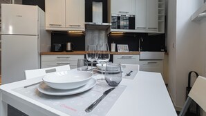 Een moderne keuken met witte kasten, een Bosch koelkast en een eettafel gedekt met borden, glazen en bestek.
