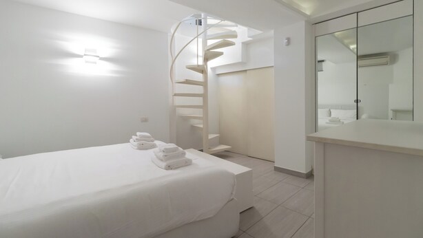Een moderne hotelkamer met een bed, een badkamer met een spiegel en een spiltrap.