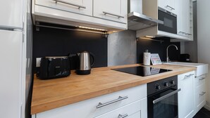 Een moderne keuken met witte kastjes, een houten aanrecht, een koffiezetapparaat en een oven.