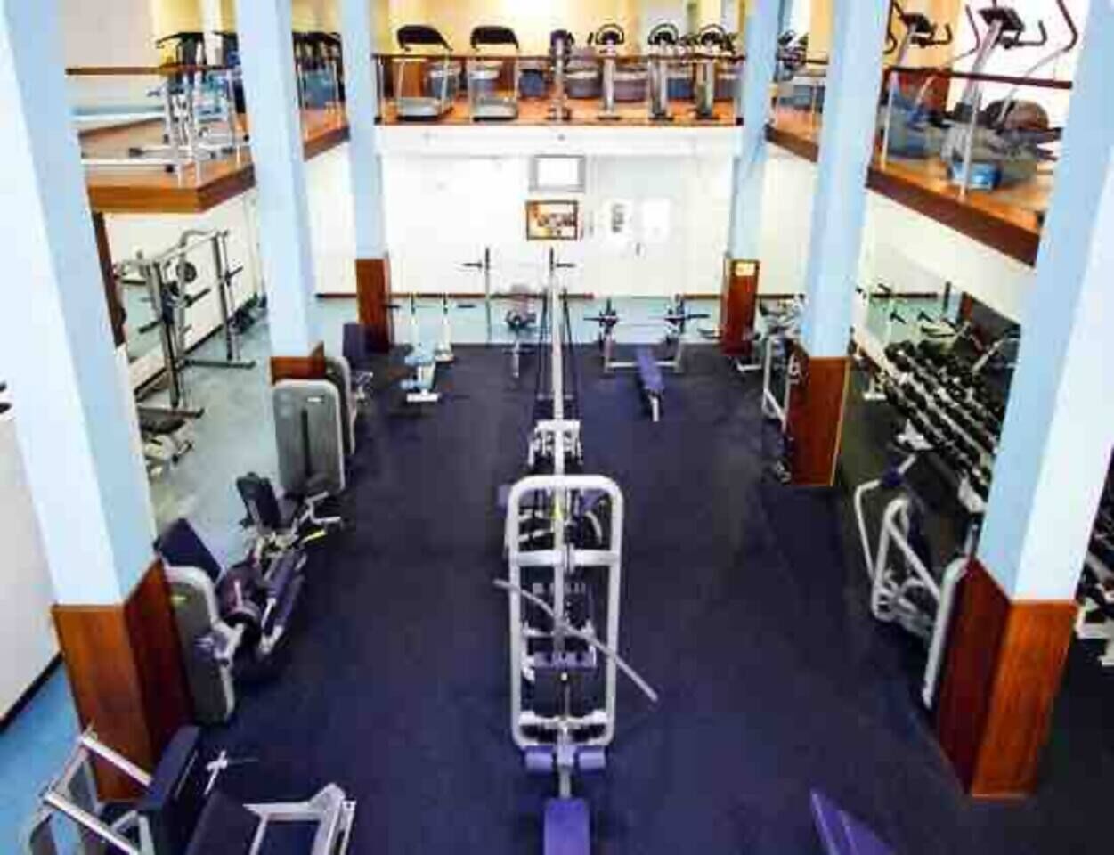 A multi-level gym with various exercise equipment, including treadmills, stationary bikes, and weight machines.