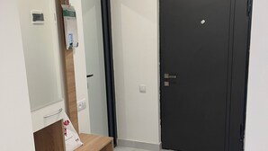 Una habitación con un armario de madera, una puerta negra y un suelo de baldosas blancas.