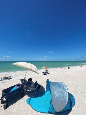 A beach scene with a clear sky, a sandy beach, and a few umbrellas.